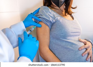 Female doctor giving the coronavirus vaccine to a young pregnant woman. Antibodies, immunize population. side effects, risk people, antibodies, new normal, covid-19. Vertical photo