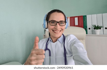 Female Doctor Giving Thumbs Up During Video Call in Office - Powered by Shutterstock