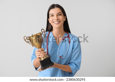 Female doctor with gold cup on light background