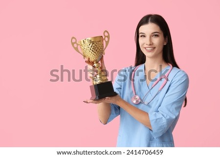 Female doctor with gold cup on pink background
