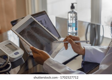 Female doctor hand holding digital tablet with chest x-ray film (CXR ) on screen and work on laptop computer at the office in clinic or hospital. Medical and health care concept. - Powered by Shutterstock