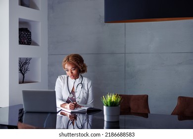 Female Doctor Having Online Seminar, Writing Notes In Planner While Taking Online Course, Working Remotely From Home Office Having Video Call With Patient