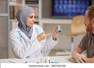 Female Doctor In Hijab Recommending Medical Equipment From Asthma To Male Patient While They Sitting At Hospital