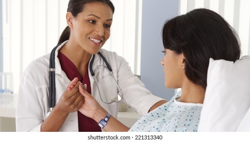 Female doctor holding Hispanic woman's hand and talking