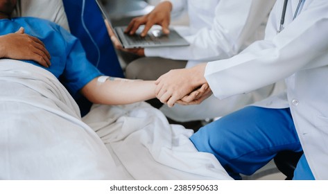 Female doctor holding male patient hand on the bed with receiving saline solution in hospital or clinic. - Shutterstock ID 2385950633