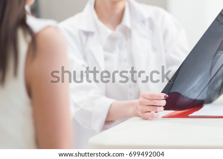 Female doctor holding  the Mammogram film image and give advice her patient in consulting room.