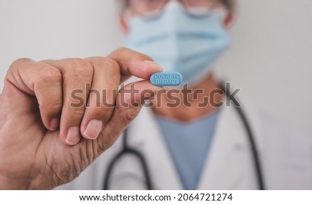 Female doctor holding the new covid antiviral pill who can halve risk of hospitalisation. This pill may cut numbers of people in hospital about a half