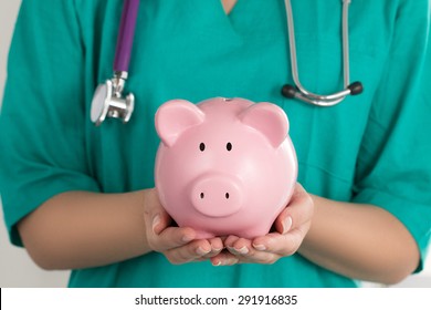 Female Doctor Holding Piggy Bank. Doctor's hands close-up. Medical insurance and health care concept.