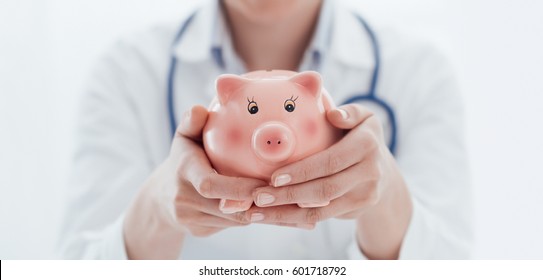 Female Doctor Holding A Piggy Bank: Health Insurance, Medical Expenses And Tax Concept