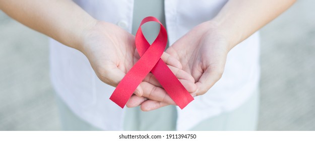 Female doctor holding red aids ribbon on hand.National Blood Donor Month in January. World aids day symbolic concept for raising supportive support on people health living with HIV on December