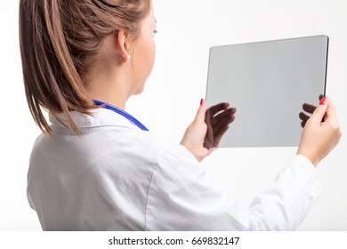 Female doctor holding a transparent tablet or virtual screen in her hands in an over the shoulder rear view isolated on white - Powered by Shutterstock