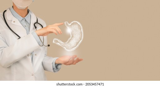 Female Doctor Holding Virtual Stomach In Hand. Handrawn Human Organ, Copy Space On Right Side, Beige Color. Healthcare Hospital Service Concept Stock Photo