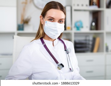 Female doctor in lab coat and protective medical masks works at the laptop