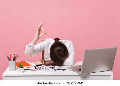 Female doctor laid her head down on desk, work on computer, medical document in hospital isolated on pastel pink background. Woman in medical gown stethoscope show ok. Healthcare medicine concept - Shutterstock ID 1319322341