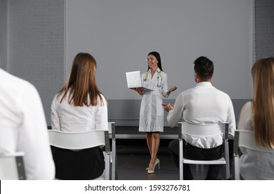 Female Doctor With Laptop Giving Lecture In Conference Room With Projection Screen