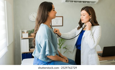 Female doctor is listening to the breathing of a female patient during a medical consultation in her office - Powered by Shutterstock