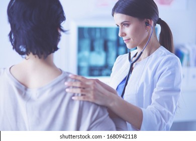 Eine weibliche Ärztin, die einem Patienten mit Stethoskop zuhört