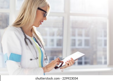 Female Doctor Looking At Medical Records On Tablet Computer