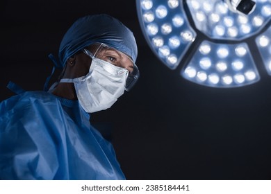 Female doctor looking at patient in operating room. Urgency, medical case. Surgeon doing surgery operation in hospital wearing gown and protective mask - Powered by Shutterstock