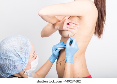Female doctor makes dotted line on female body for cellulite correction. cosmetic surgery. lifting and breast augmentation.