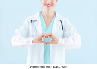 Female Doctor Making Heart With Hands On Light Background