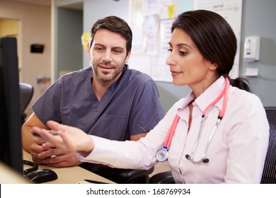 Female Doctor With Male Nurse Working At Nurses Station