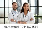 a female doctor and a male doctor are standing in the office with their arms crossed