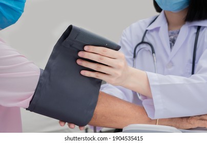 Female Doctor Measuring Blood Pressure Of Senior Woman At Home, Wearing Medical Mask To Protect From Spreading Virus, Healthcare Concept