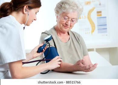 Female Doctor Measuring Blood Pressure Of Senior Woman