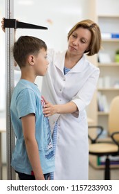 Female Doctor Measuring Height Of Child Boy In Clinic