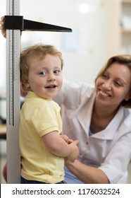 Female Doctor Measuring Height Of Child Boy In Clinic