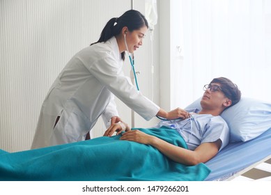 Female Doctor Is Measuring The Pulse Of Asian Patient Male Who Is Lying In Bed.