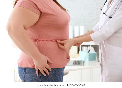 Female doctor measuring waist of overweight woman with measuring tape in clinic