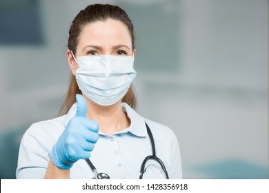 female doctor with medical face mask and medical gloves shows thumb up
