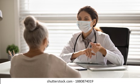 La dottoressa in maschera facciale medica ha consultato un paziente anziano durante le pandemie di covid-19. Il medico di famiglia in chiacchiere con maschera facciale consulta il cliente maturo in clinica o in ospedale. Concetto di coronavirus.