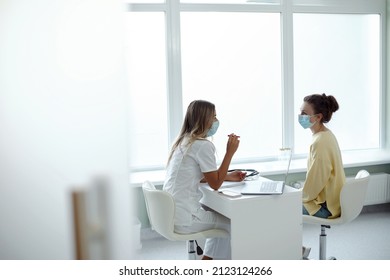 Female Doctor In Medical Facial Mask Have Consultation With Patient During Covid-19 Pandemics. Woman In Facemask Talk Consult  Client In Clinic Or Hospital. Coronavirus Concept.