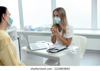 Female Doctor In Medical Facial Mask Have Consultation With Patient During Covid-19 Pandemics. Woman In Facemask Talk Consult  Client In Clinic Or Hospital. Coronavirus Concept.