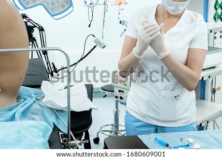 A female doctor in a medical mask and latex gloves is preparing to vaccinate a patient against viral diseases. Syringes with antivirus on the table. Coronavirus pandemic.