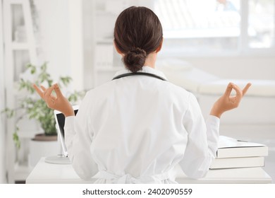 Female doctor meditating in clinic, back view - Powered by Shutterstock