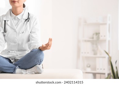 Female doctor meditating on couch in clinic - Powered by Shutterstock