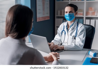 Female Doctor Meeting A Patient In Her Office For A Medical Consultation, They Are Wearing Surgical Masks