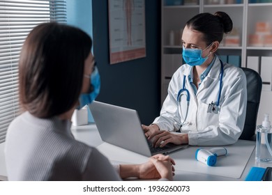 Female Doctor Meeting A Patient In Her Office For A Medical Consultation, They Are Wearing Surgical Masks