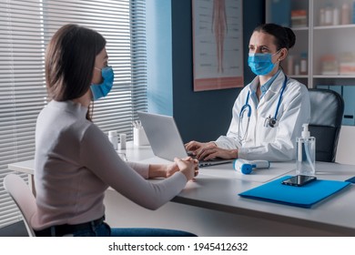 Female Doctor Meeting A Patient In Her Office For A Medical Consultation, They Are Wearing Surgical Masks