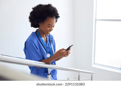 Female Doctor Or Nurse Browsing On Mobile Phone On Stairs In Hospital - Powered by Shutterstock