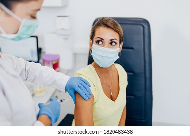 Female doctor or nurse giving shot or vaccine to a patient's shoulder. Vaccination and prevention against flu or virus pandemic.  - Shutterstock ID 1820483438