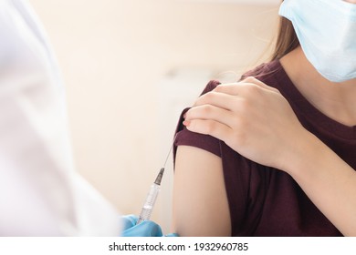 female doctor or nurse giving shot or vaccine injection to a teenager patient. Vaccination and prevention against flu or virus pandemic