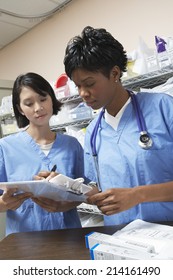 Female Doctor And Nurse In Hospital Doing Paperwork