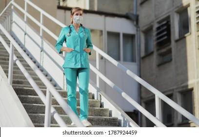 Female Doctor Or Nurse In A Protective Face Mask Walking Up The Stairs