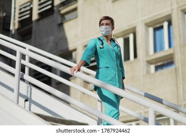 Female Doctor Or Nurse In A Protective Face Mask Walking Up The Stairs