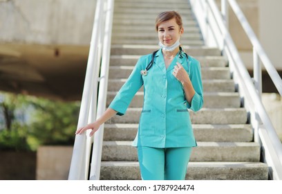 Female Doctor Or Nurse In A Protective Face Mask Walking Up The Stairs